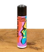 Ein einzelnes Clipper Feuerzeug aus der "Gizeh Faces Vol. 1" Serie mit einem farbenfrohen Gesichterdesign auf einer Holzoberfläche.