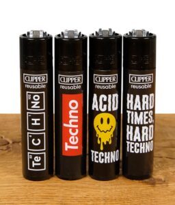 Vier Clipper-Feuerzeuge im Techno-Design auf einem Holztisch vor einem weißen Hintergrund. Jedes Feuerzeug hat ein individuelles Techno-Motiv.