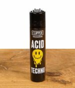 Clipper Feuerzeug mit "Acid Techno" Design, schwarzes Gehäuse mit gelbem Smiley und Schriftzug.