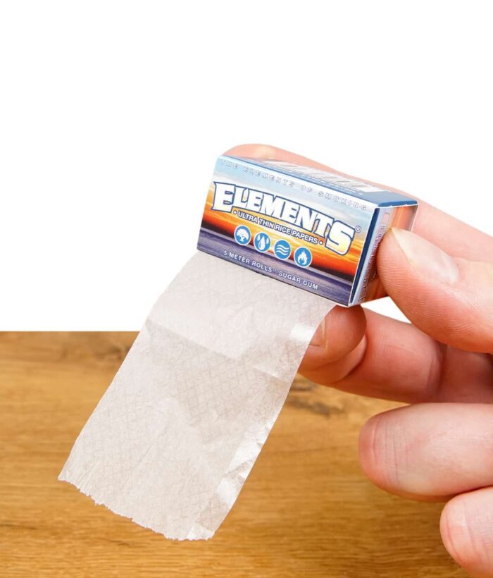 Hand hält eine Schachtel Elements Ultra Thin Rolls, zeigt das ultradünne Reispapier.