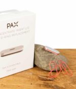 Nahaufnahme des PAX Concentrate Insert Lid und O-Ring Ersatzteile auf einem Holztisch, neben der Originalverpackung liegend.