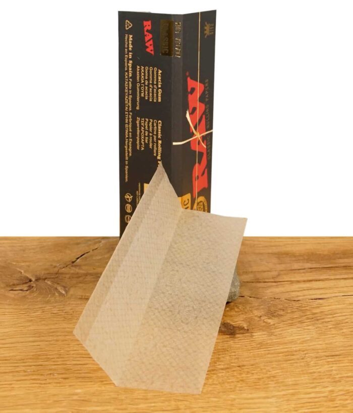 Eine Packung RAW Black King Size Papers, geöffnet, mit einem einzelnen Blättchen davor. Extrafeine, langsambrennende Blättchen für King Size Joints.