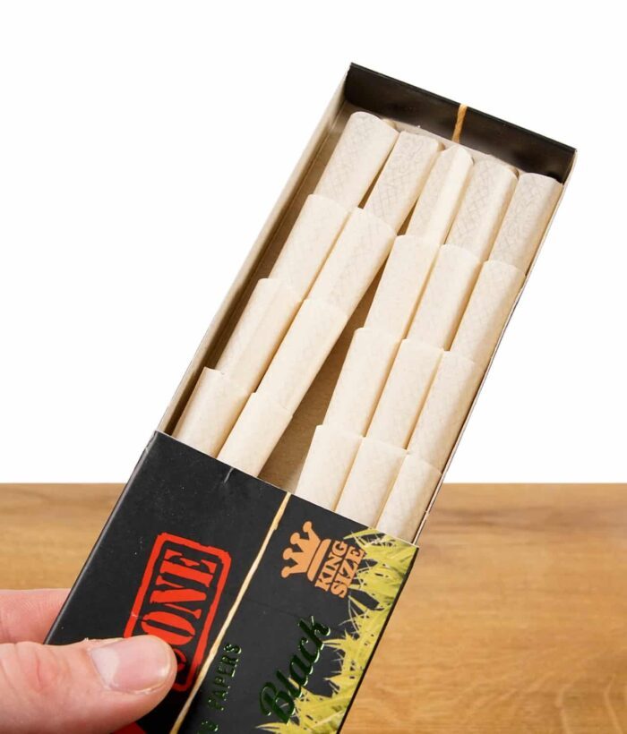 RAW Black Organic King Size Pre-Rolled Cones in einer geöffneten Packung, gehalten von einer Hand.