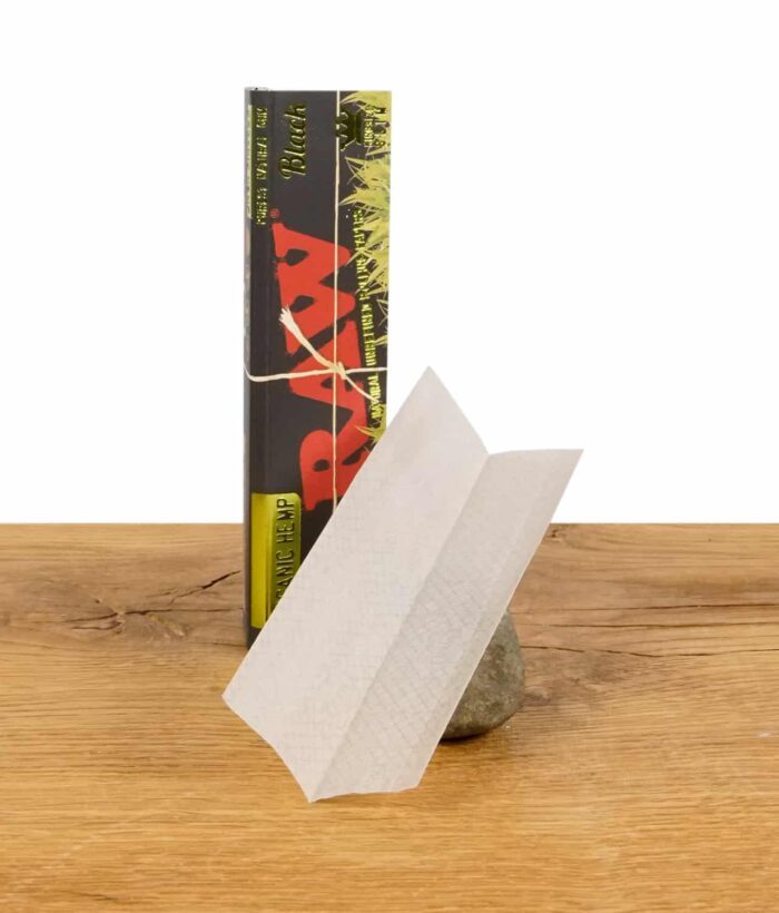 RAW Black Organic Hemp Rolling Paper im King Size Slim Format, ein einzelnes Blatt vor der Packung präsentiert
