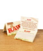 RAW Organic Hemp Rolling Papers 1 1/2 Size Packung neben Stein auf Holzuntergrund