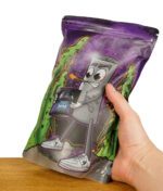 Hand, die eine bunte Verpackung einer veganen Kokosaktivkohle mit Cartoon-Design hält.
