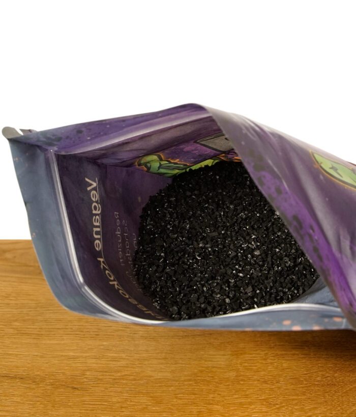 Geöffnete Verpackung einer veganen Kokosaktivkohle mit sichtbarer Kohle in Granulatform.
