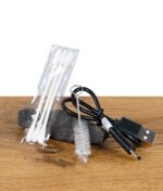 Reinigungszubehör und USB-Kabel des XMax V3 Pro Vaporizers auf Holzoberfläche.
