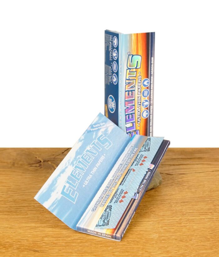 Geöffnete Packung Elements King Size Ultra Thin Papers, zeigt das Innere mit bedrucktem Papier und Acacia-Gummierung, auf einem Holztisch.