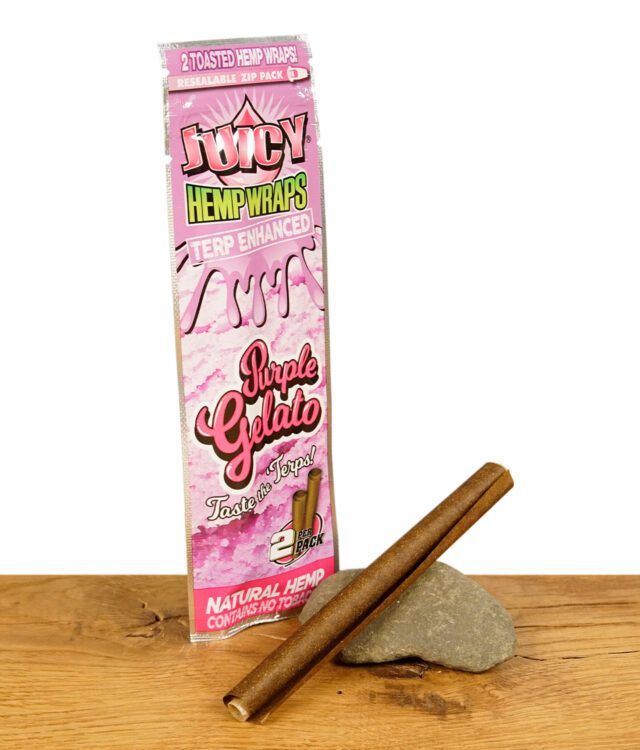 Juicy Hemp Wraps Purple Gelato Verpackung mit einem vorgerollten Hanf-Wrap daneben, auf einem Stein liegend.