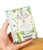 Hand hält die Packung des Nature of Spirit Tabakersatzes in der "Soft"-Variante mit dem Aufdruck "Smoking can be deadly".
