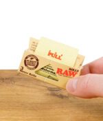 Hand hält RAW Classic Rolls King Size Zigarettenpapierpackung, zeigt Ziehanweisung.