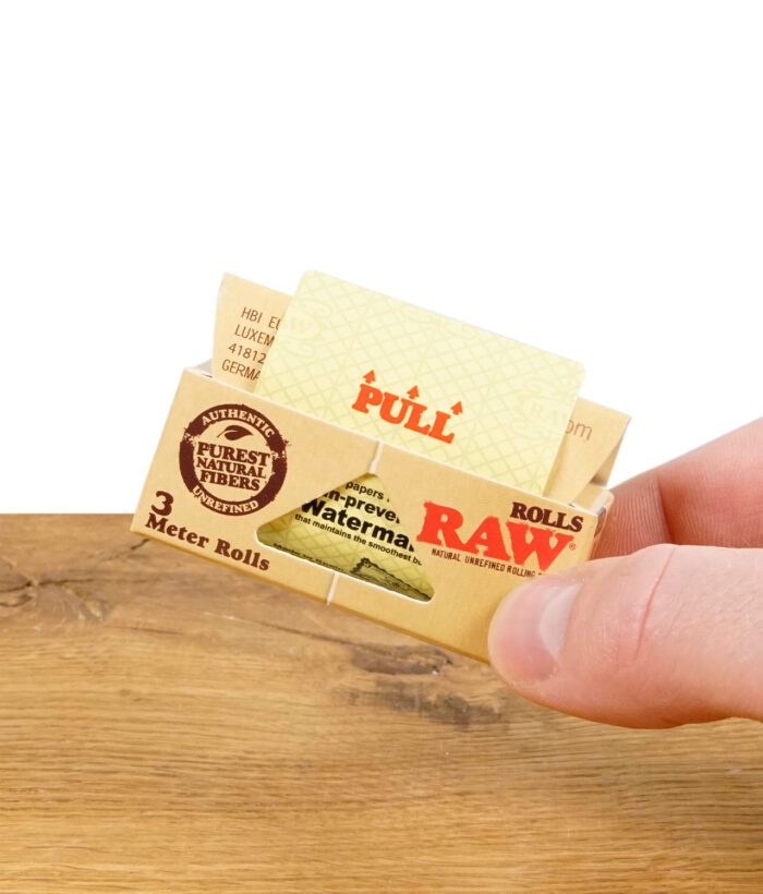 Hand hält RAW Classic Rolls King Size Zigarettenpapierpackung, zeigt Ziehanweisung.