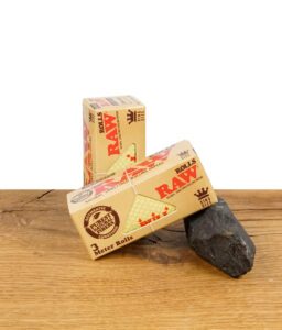 RAW Classic Rolls King Size Zigarettenpapier auf Holz, Verpackung und Papierrolle sichtbar.