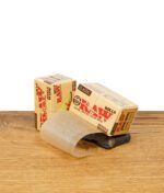 RAW Classic Rolls Single Wide Zigarettenpapier auf Holz, Papierrolle teilweise entrollt.