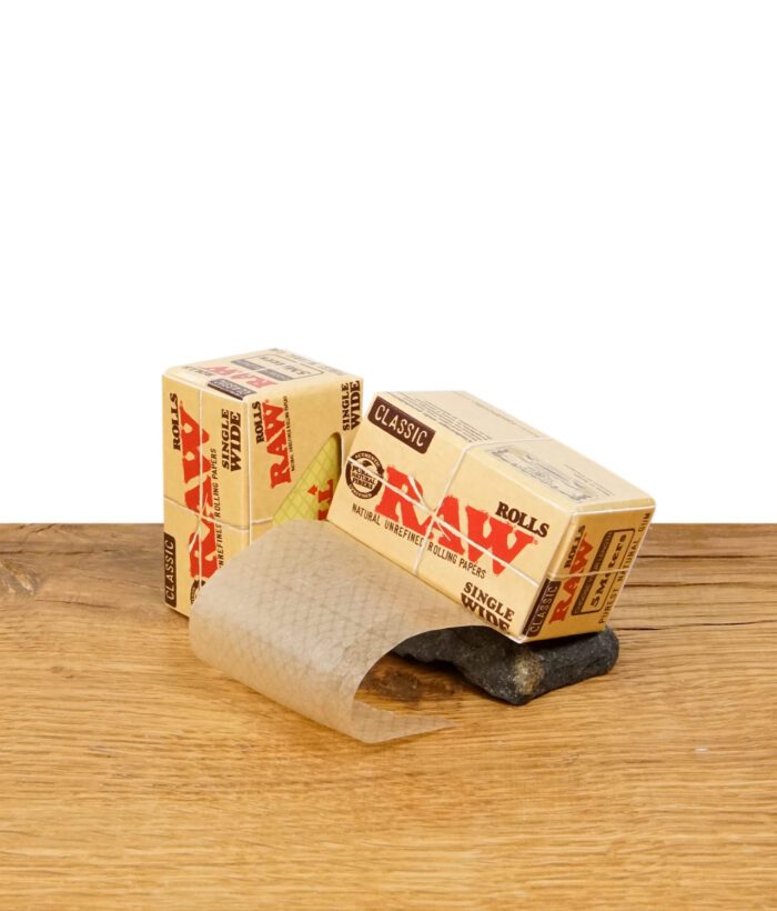 RAW Classic Rolls Single Wide Zigarettenpapier auf Holz, Papierrolle teilweise entrollt.