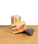 RAW Classic Rolls Single Wide Zigarettenpapier auf Holzoberfläche, Verpackung sichtbar.