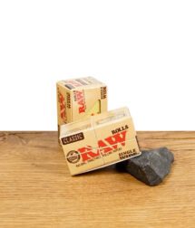 RAW Classic Rolls Single Wide Zigarettenpapier auf Holzoberfläche, Verpackung sichtbar.