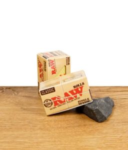 RAW Classic Rolls Single Wide Zigarettenpapier auf Holzoberfläche, Verpackung sichtbar.