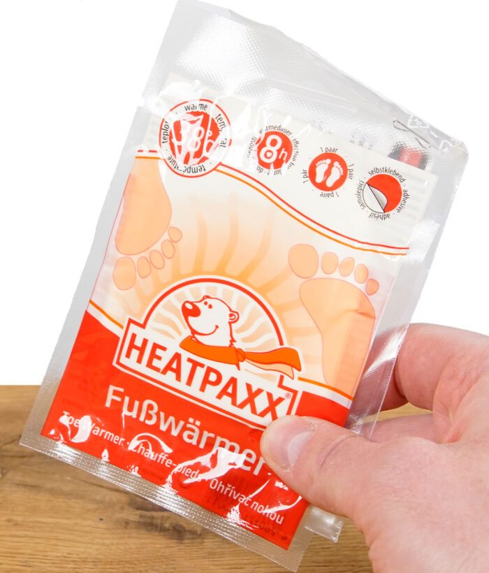 Hand die ein rotes Fußwärmer Pack hält