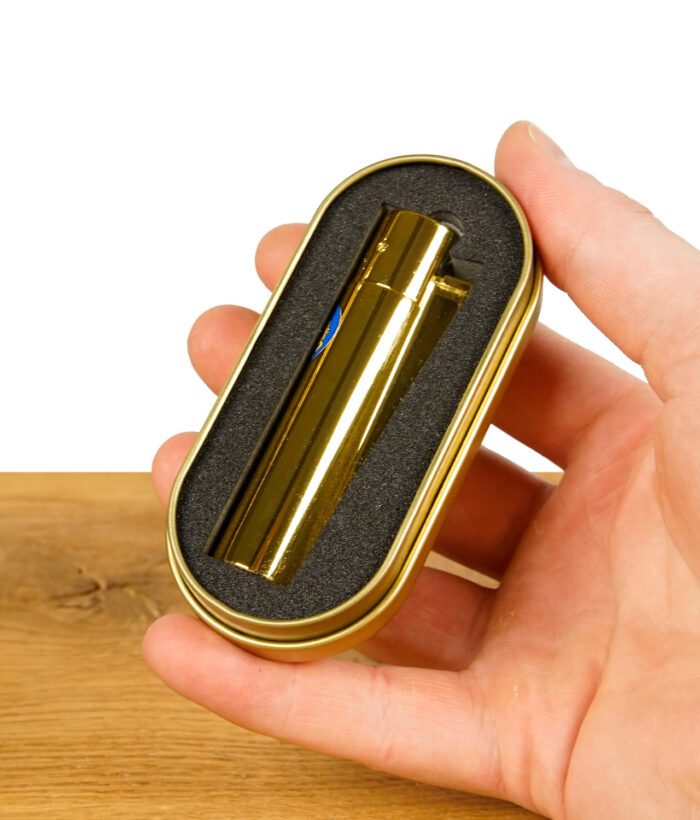 Goldenes Metal Feuerzeug in einer Schutzhülle aus Schaumstoff in einer Metallbox, gehalten von einer Hand.