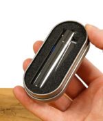 Silbernes Clipper Metal Feuerzeug in einer Schutzhülle aus Schaumstoff in einer Metallbox, gehalten von einer Hand.
