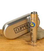 Silbernes Clipper Metal Feuerzeug mit The Bulldog Logo neben einer silbernen Clipper Metallbox auf Holzuntergrund.