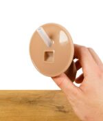 Unterseite des ScreenyWeeny 6.0 Fake-Penis, der einen Anschluss für synthetischen Urin zeigt, auf einem Holztisch.