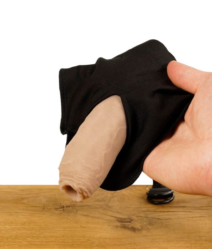 ScreenyWeeny 6.0 Fake-Penis in einem schwarzen Halter, der von einer Hand gehalten wird, auf einem Holztisch.