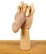 Holzmodell einer Hand, die den ScreenyWeeny 6.0 Fake-Penis in Hautfarbe auf einem Holztisch hält.