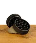 Bio Hanf Grinder von Tyson 2.0 mit rotem T Logo auf einem Stein aufgeteilt in zwei Teile