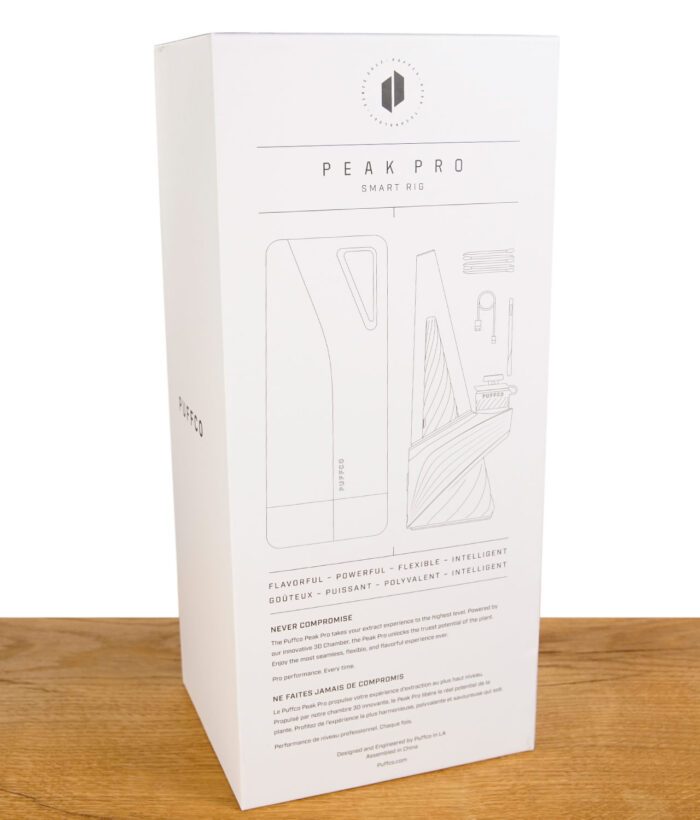 Puffco New Peak Pro Verpackung von hinten auf Holztisch, vor weißem Hintergrund