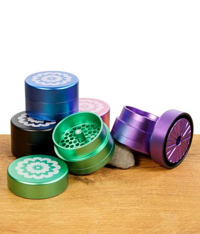 Flower Mill Grinder 63 mm in fünf Farben – geöffnet und geschlossen auf Holzfläche