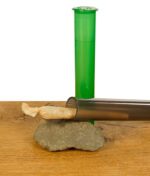 Zwei Jointtubes auf einem Stein mit geöffnetem Deckel vor weißem Hintergrund auf einem Holzbrett