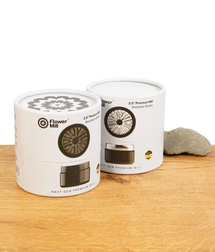 Flower Mill Next Gen Edelstahl und Aluminium Grinder in Verpackung auf einem Holztisch und weißem Hintergrund