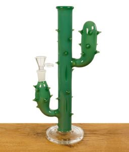 Grüne Glasbong in Kaktus-Optik mit Dornendetails und rundem Standfuß, präsentiert auf einem Holztisch.