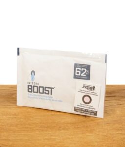  Integra Boost 2-Way Humidity Regulator mit 62% relativer Luftfeuchtigkeit, auf einem Holztisch liegend, vollständige Verpackung sichtbar.