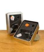 Zwei geöffnete Metallboxen mit Glasbanger-Set und bunten Carb Caps auf Holztisch