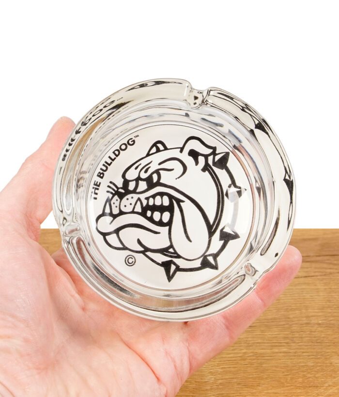 The Bulldog Amsterdam Glas-Aschenbecher in einer Hand gehalten, mit sichtbarem Logo und Zigarrenmulden.