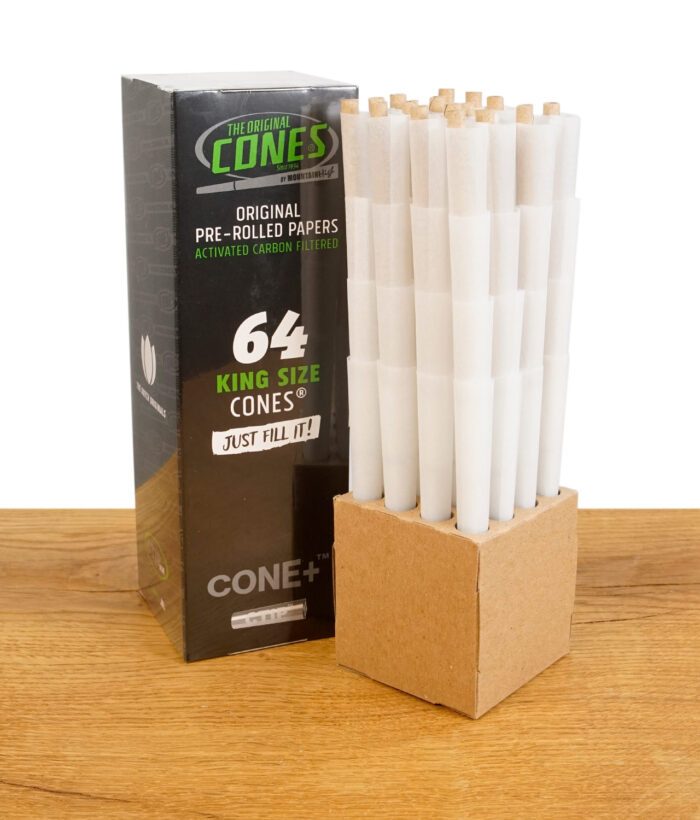 Verpackung der "The Original Cones" King Size mit 64 vorgedrehten Filterhülsen und aktivierter Kohlefilterung, zusammen mit der gestapelten Halterung auf einem Holztisch.