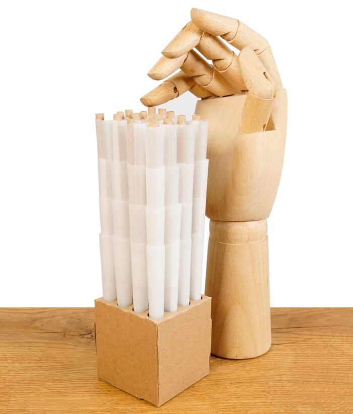 Stapel der vorgedrehten Filterhülsen aus der "The Original Cones" King Size Packung, präsentiert in einer Halterung neben einer Holzhand, auf einem Holztisch.