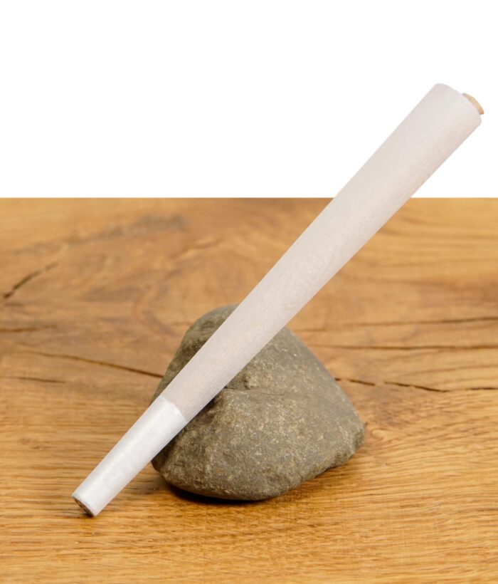 Einzelne vorgedrehte Filterhülse aus der "The Original Cones" King Size Packung, liegend auf einem Stein auf einem Holztisch.