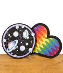 Zwei Dab-Mats in Herz- und Kreisform mit Regenbogen- und Weltraumdesign, auf Holzuntergrund.