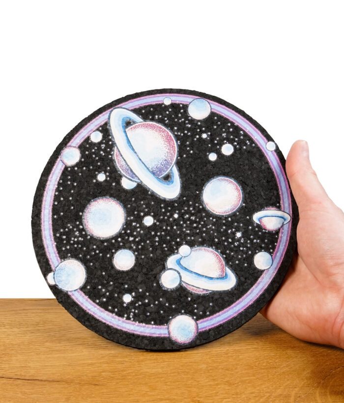 Hand hält runden Dab-Mat mit detailliertem Planeten- und Weltraummotiv.