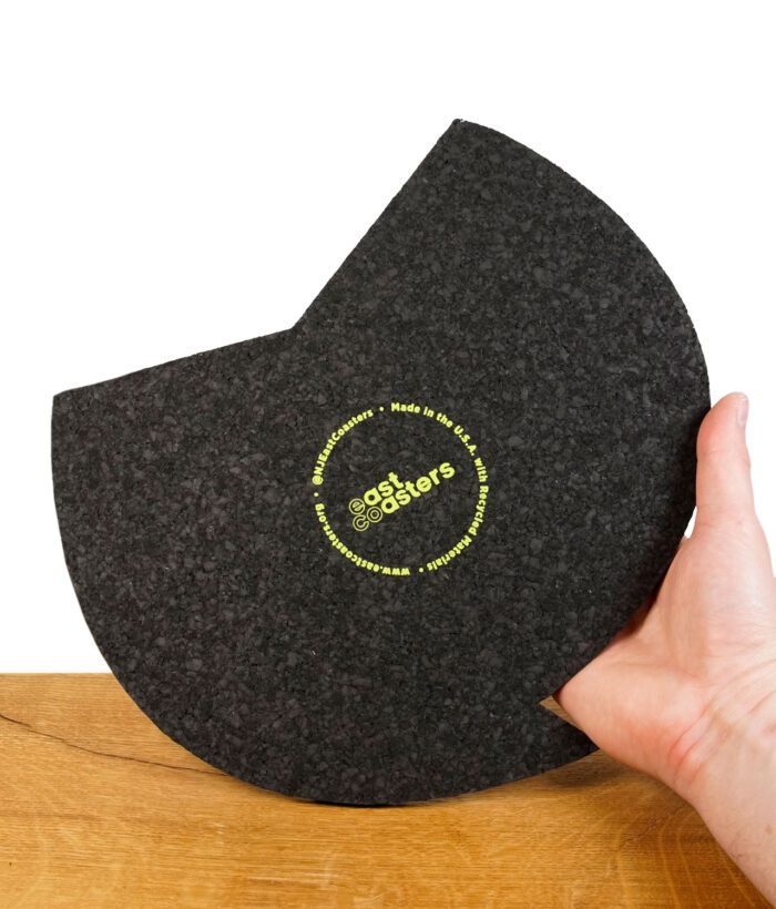 Schwarzer East Coasters Dab-Mat mit grünem Logo, gehalten über einem Holzuntergrund.