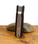 Rückseite des Everyday Canna Co. Multipass Cannabis-Tools mit EDC-Logo und Gravur „Designed & Engineered in the USA“, stehend auf einem Stein.