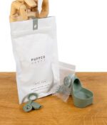 Puffco Proxy Travel Pack in Grün mit Verpackung, Zubehör und Silikonhalterung, präsentiert von einer Holzhand.