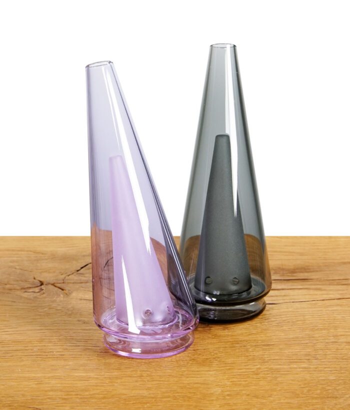 Zwei Puffco Peak Pro Glasaufsätze in Lila und Schwarz auf Holzuntergrund.