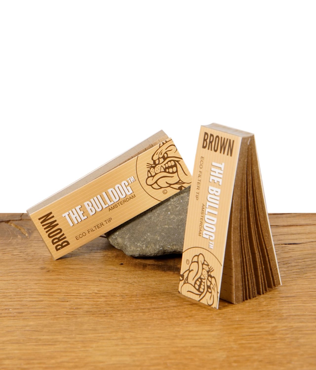 Zwei Packungen The Bulldog Brown Eco Filter Tips, eine stehend, eine liegend auf dekorativem Stein.