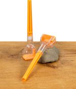 Zwei orangefarbene Cone-Artist Drehhilfen aus Kunststoff und Glas auf einem Holztisch.